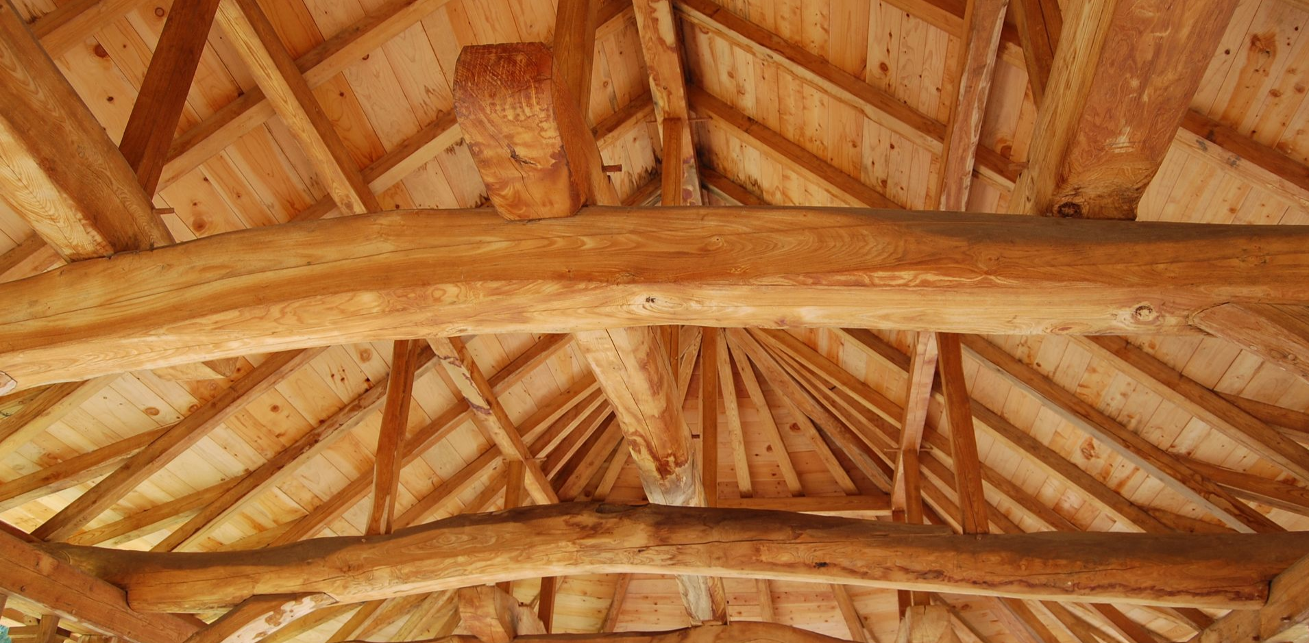 Intérieur avec charpente apparente en bois, poutres et chevrons apparents.