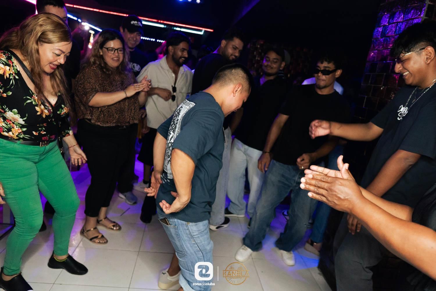 Gente bailando en una discoteca, con luces de colores y una pista de baile abarrotada.