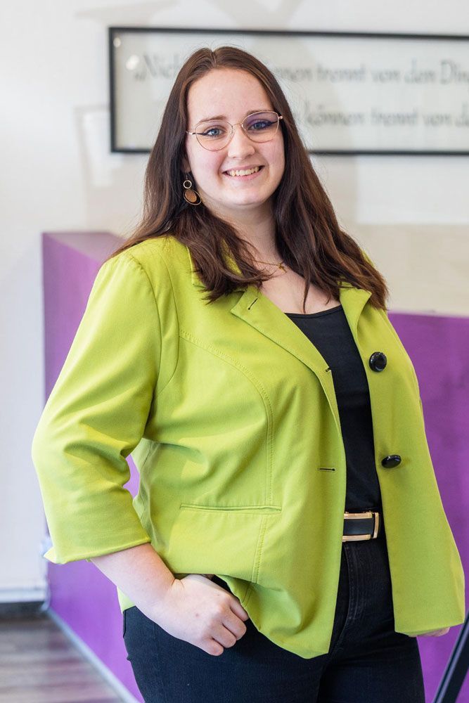 eine junge frau mit brille und halskette lächelt in die kamera .