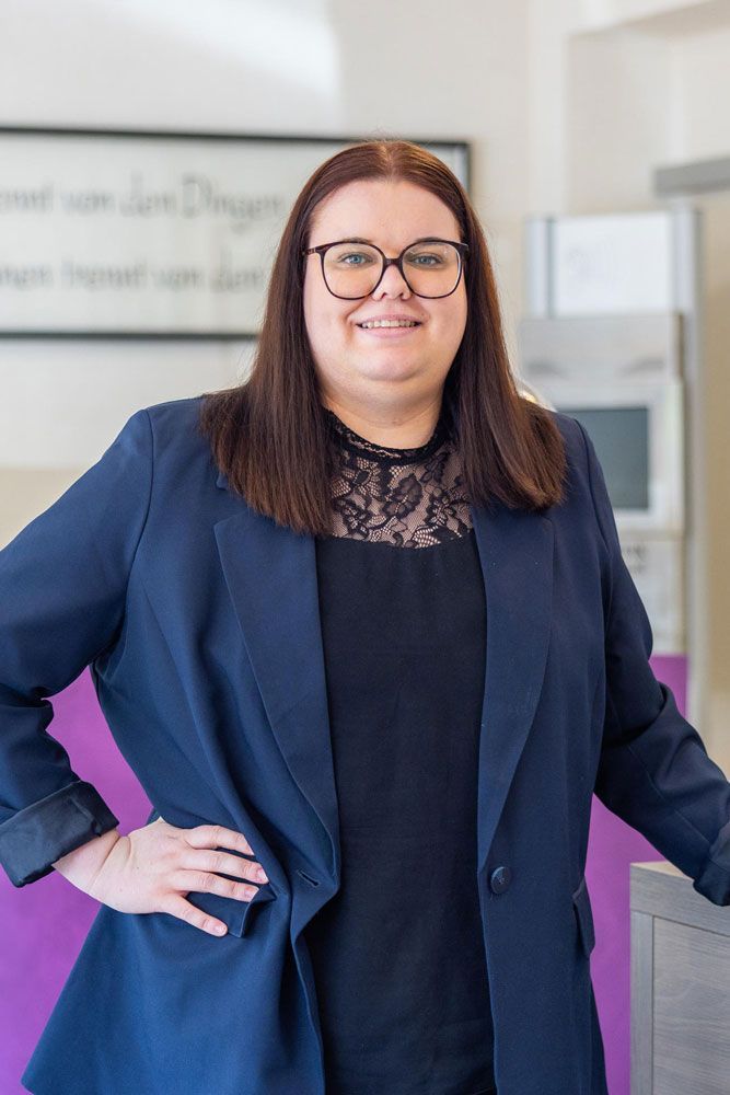 Eine Frau mit Brille und Halskette lächelt in die Kamera .