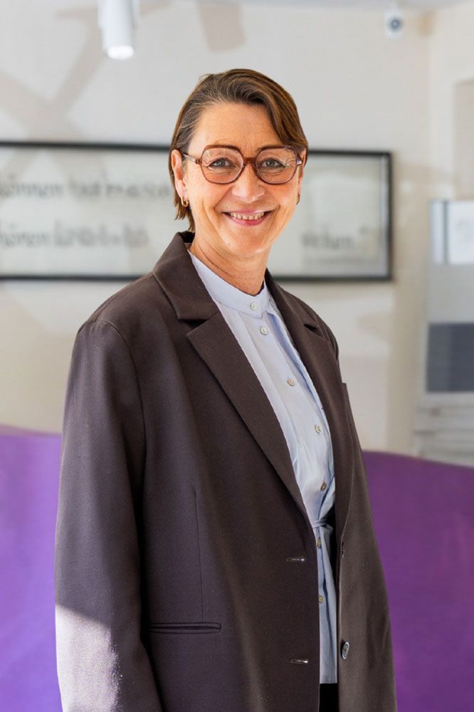 Eine Frau trägt ein schwarzes Lederhemd und lächelt in die Kamera .