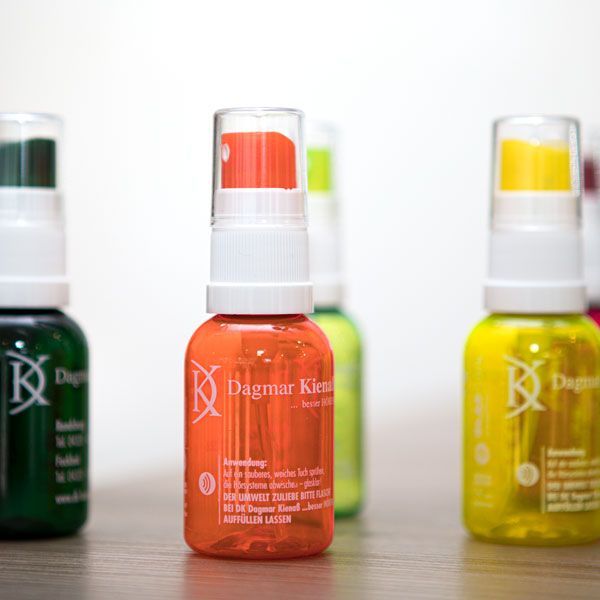 eine kleine orangefarbene Flasche steht auf einem Tisch neben anderen Flaschen .