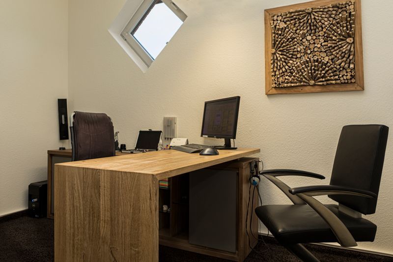 ein Schreibtisch mit einem Computer und einem Bild an der Wand