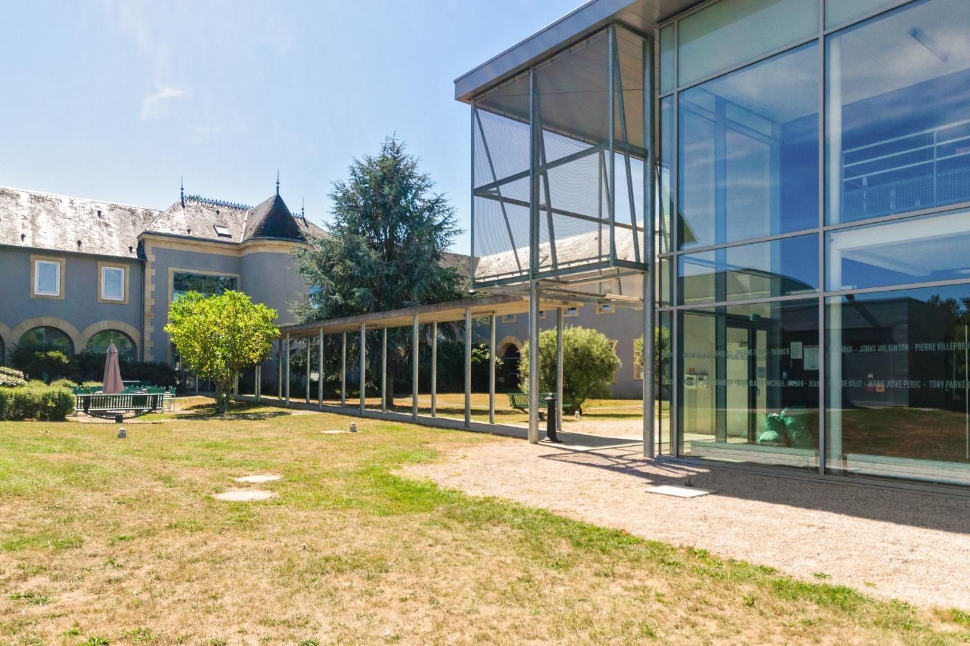 Une grande maison avec des murs de verre et une grande pelouse.