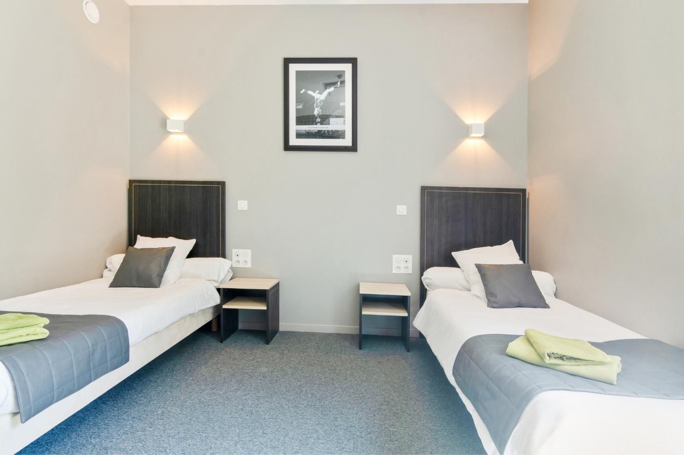 Deux lits dans une chambre d'hôtel avec tapis bleu.