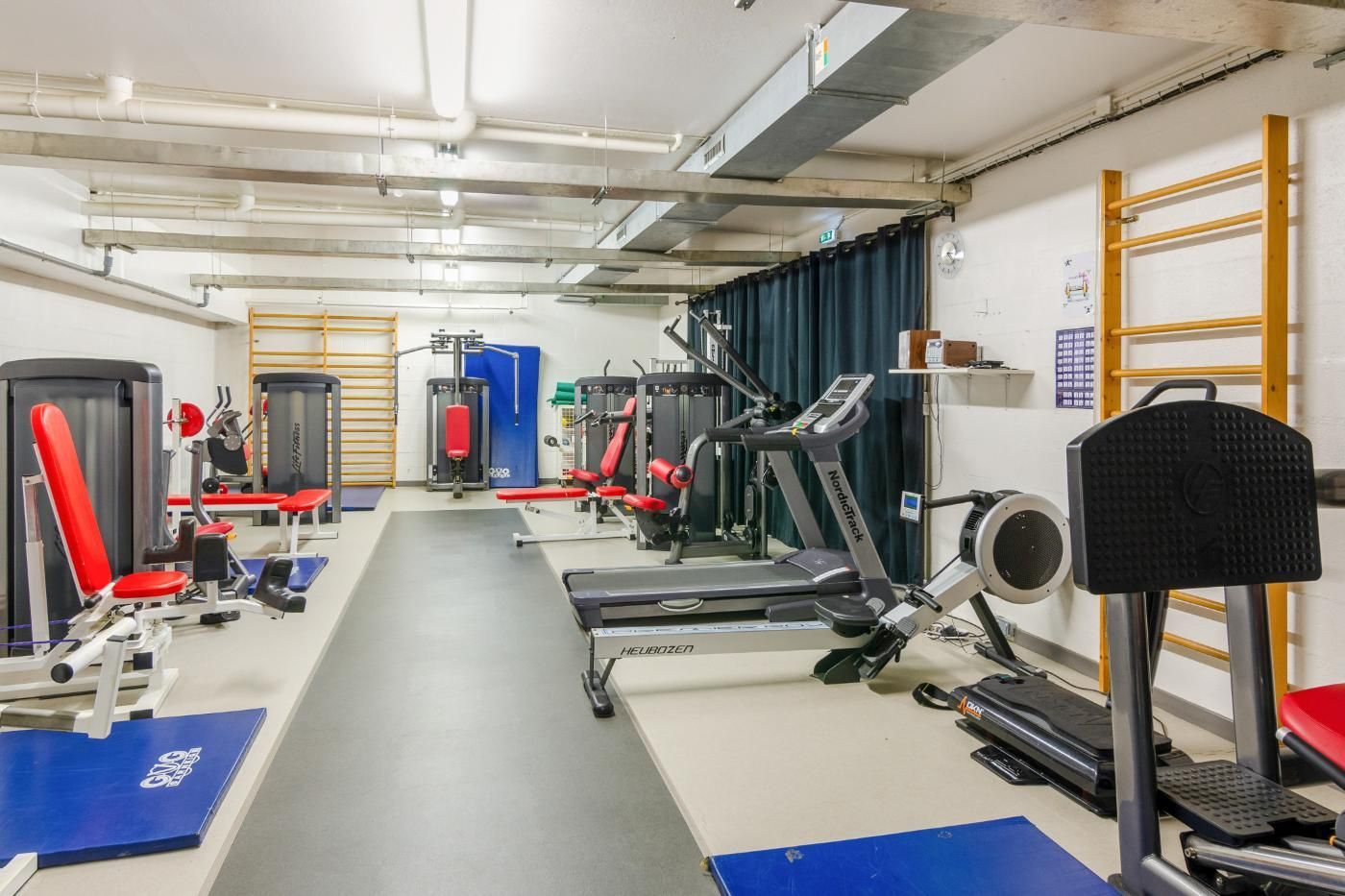 Une salle de gym avec une rangée d'équipements d'exercice.