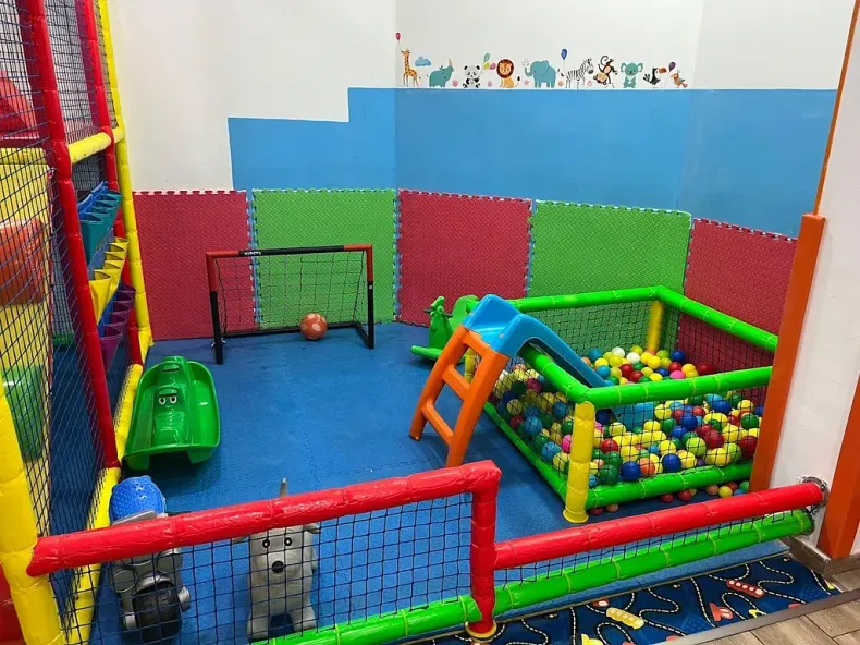 Hay una piscina de pelotas con un tobogán y una portería de fútbol.