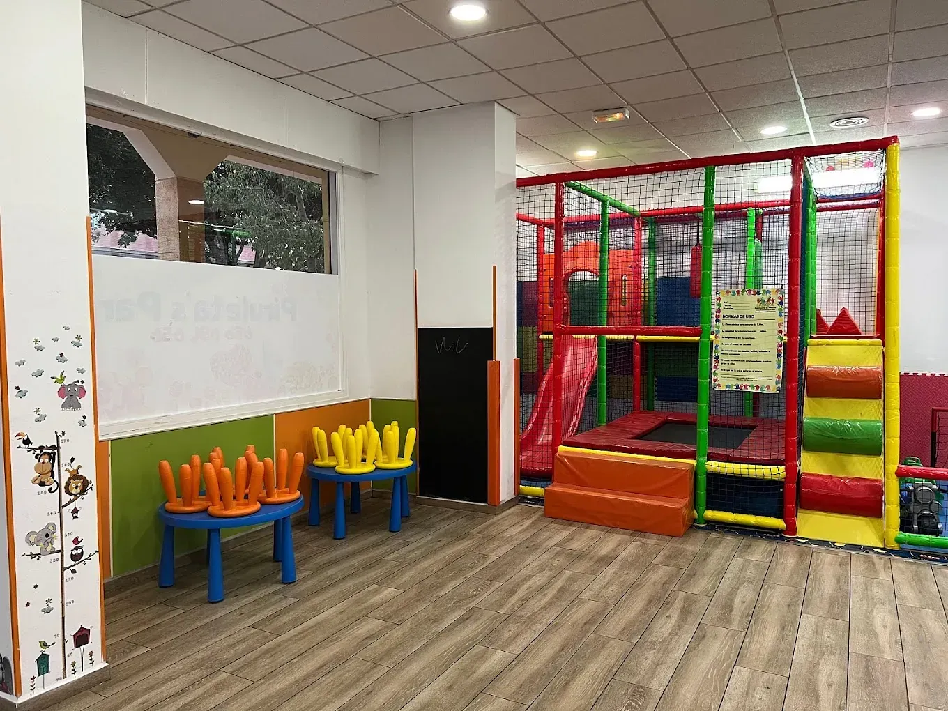Una habitación con un patio de juegos y mesas y sillas en ella.