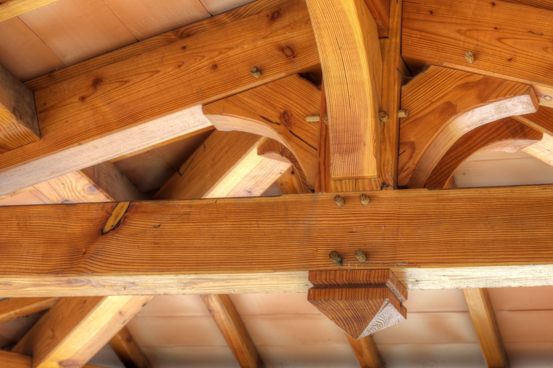 Poutres de toit en bois avec supports décoratifs en arc, couleur marron clair.