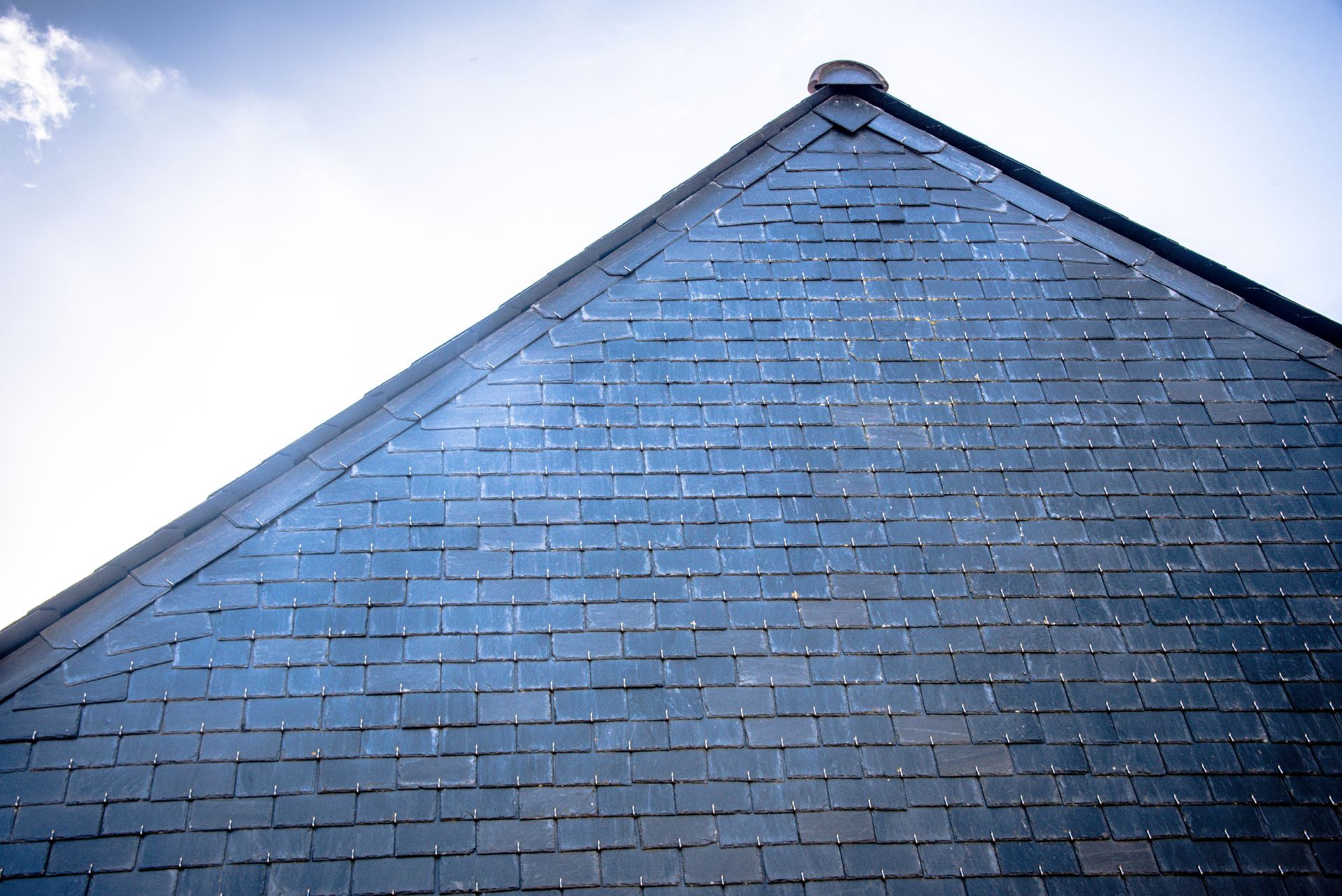 Toit en tuiles gris foncé avec un ciel clair en arrière-plan.