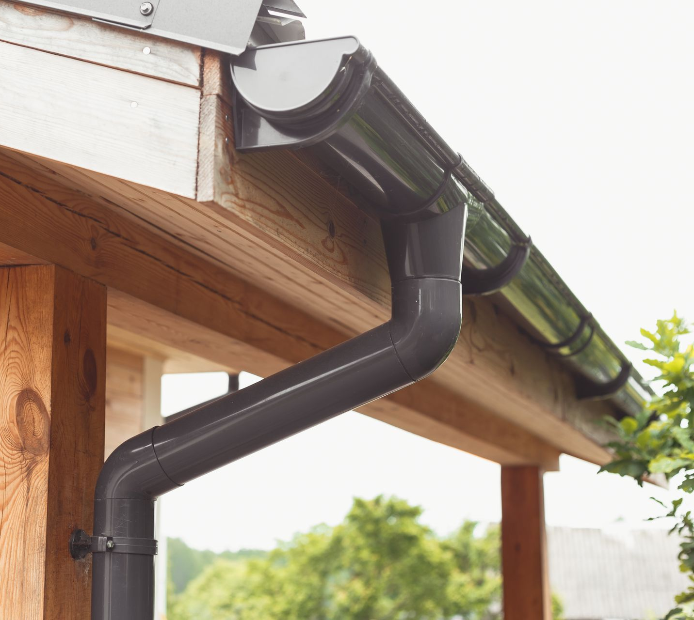 Système de gouttière gris foncé fixé sur un toit en bois.