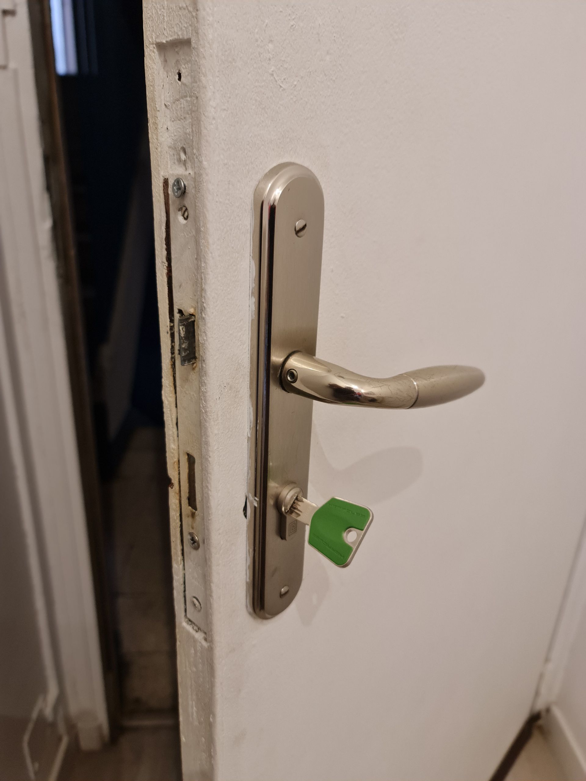 Clés dans la serrure d'une porte rouge légèrement ouverte.