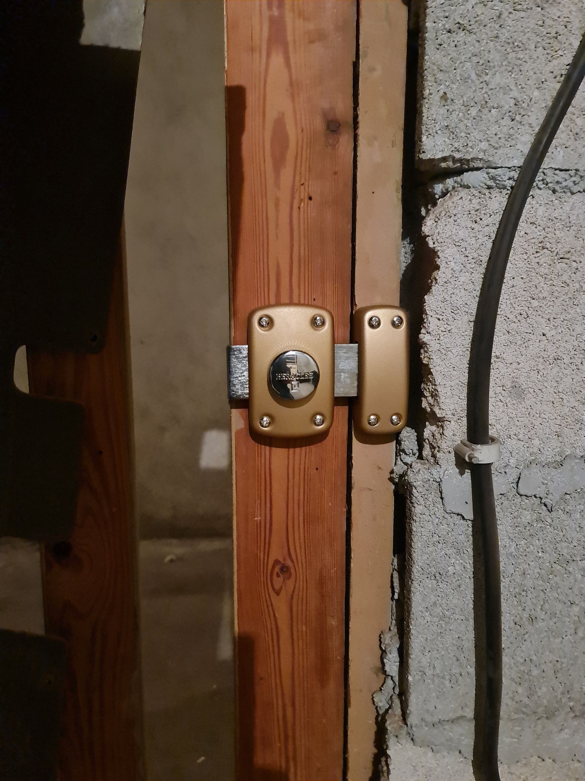 Gros plan sur un portail en métal blanc avec un cadenas en laiton et une serrure, sur une allée en briques.