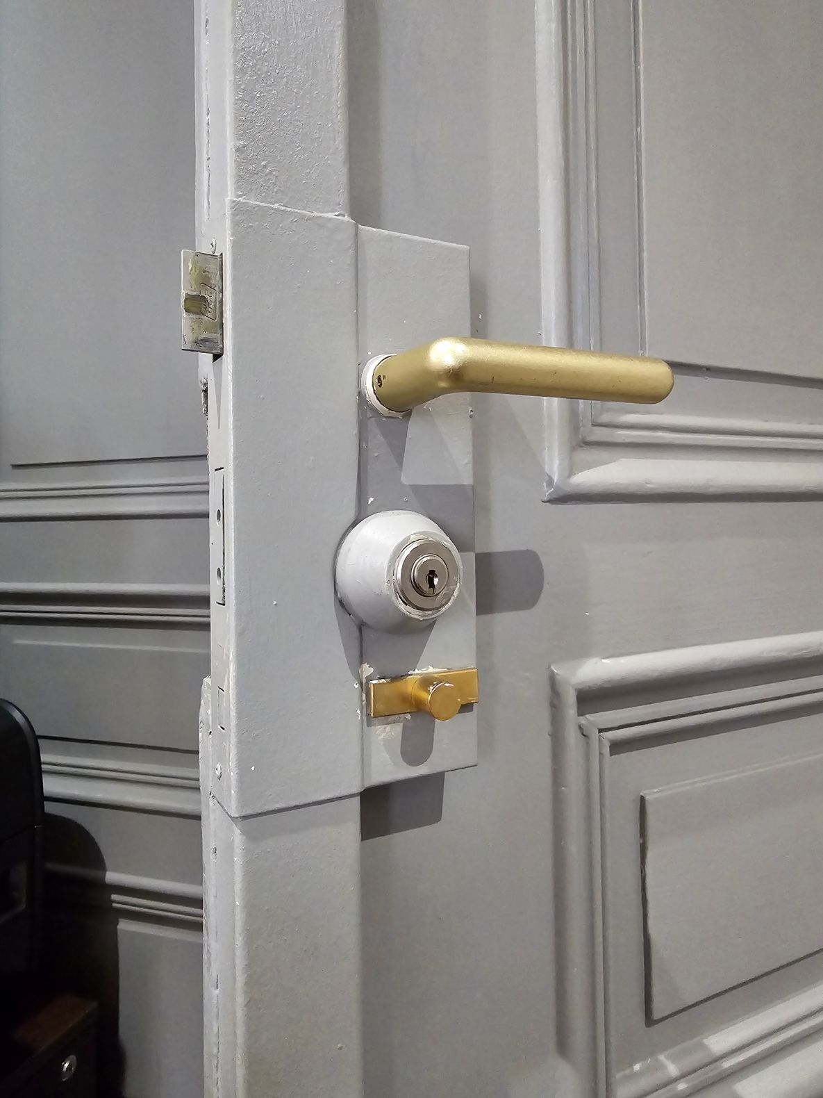 Gros plan sur un loquet et une gâche en laiton sur un cadre de porte en bois.