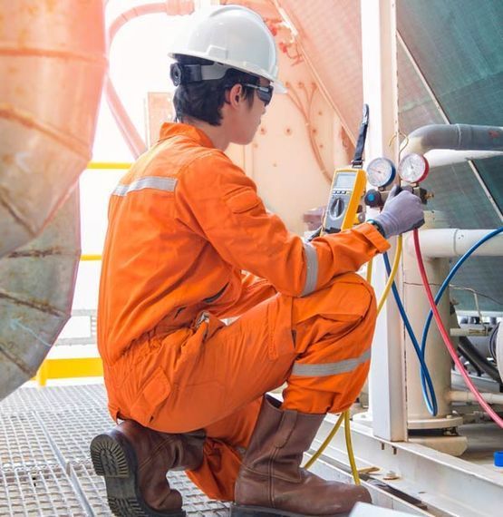 Un hombre con un mono naranja está trabajando en una máquina.