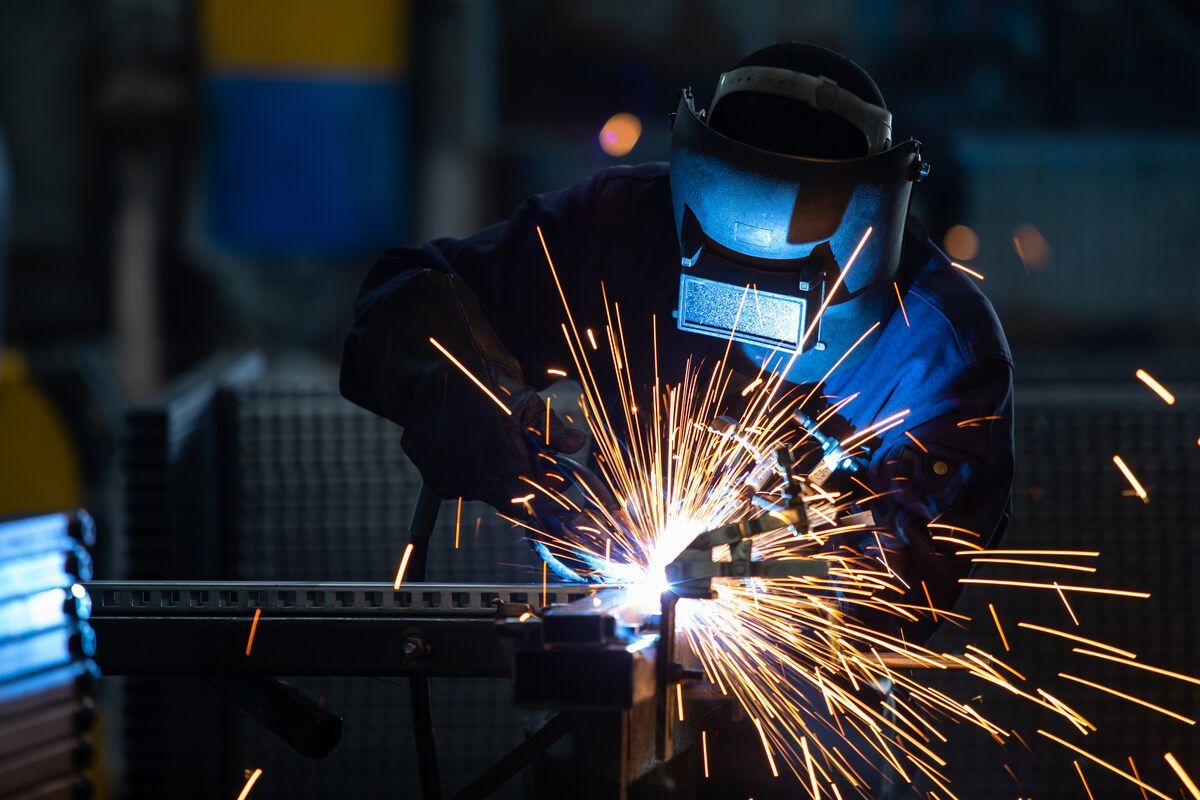 Ein Mann schweißt in einer Fabrik ein Stück Metall.