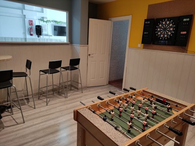 Una habitación con una mesa y sillas y un tablero de dardos en la pared.