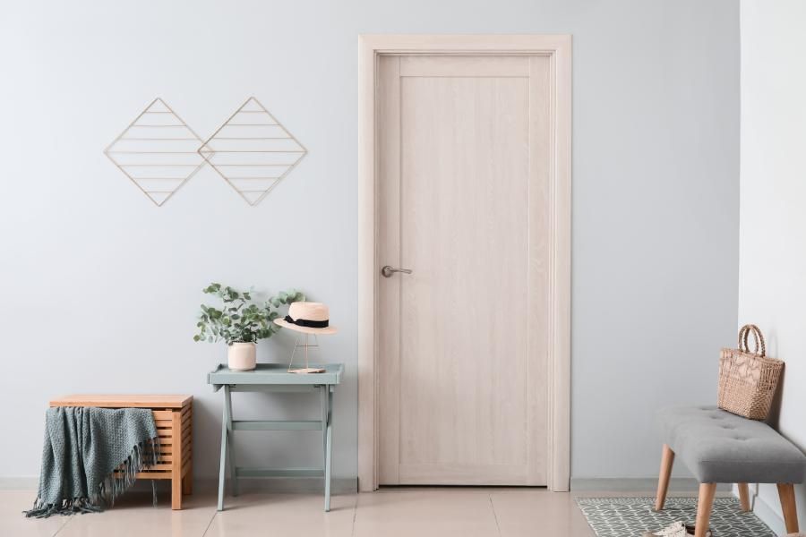 Ein Flur mit einer weißen Tür und einem Tisch mit einer Pflanze darauf.