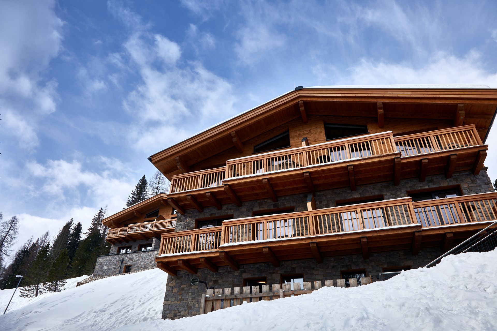 Holzchalet mit Steinsockel, Balkonen, in verschneiter Landschaft