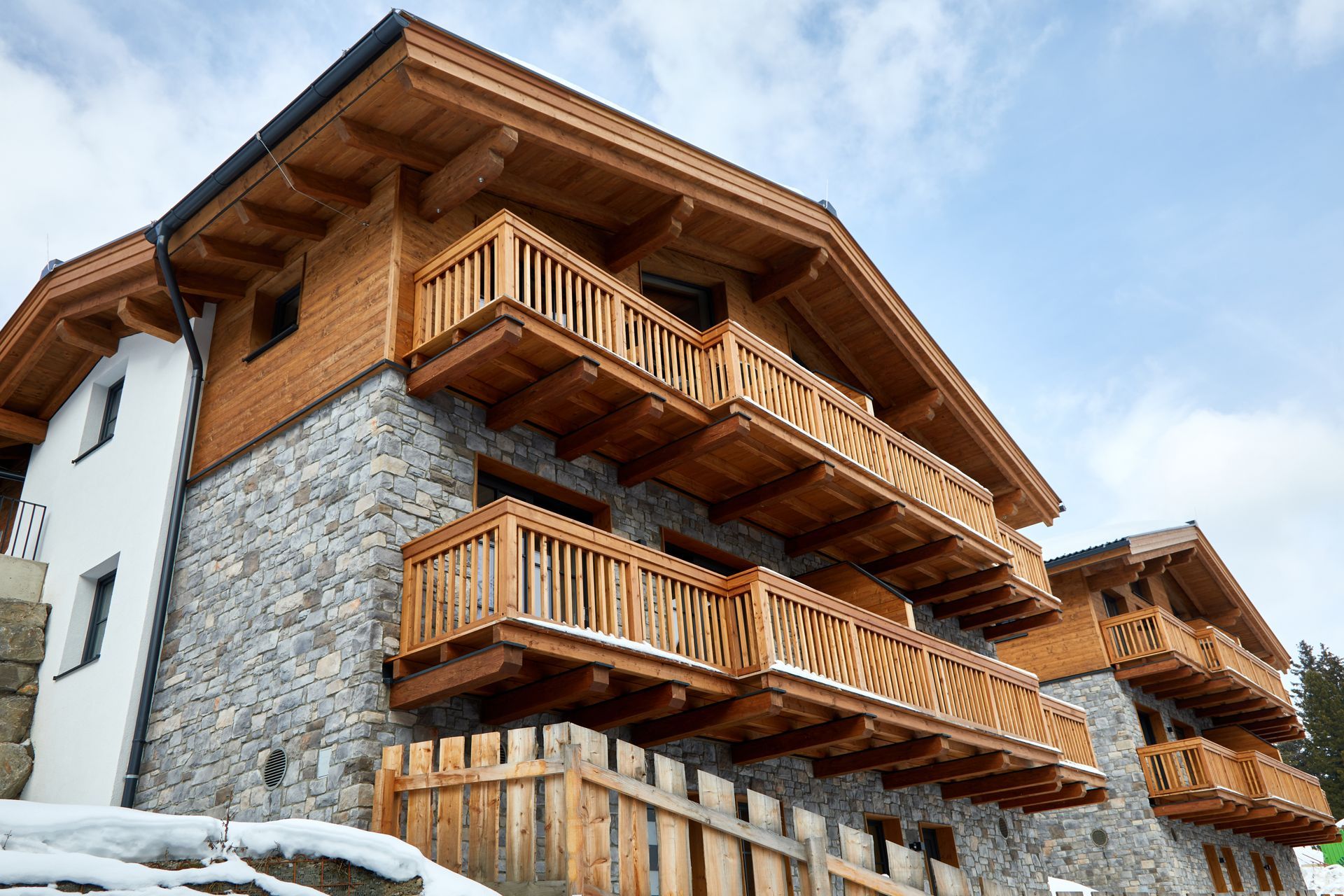 Holzchalet mit Steinmauern, Balkonen und Schnee auf dem Boden