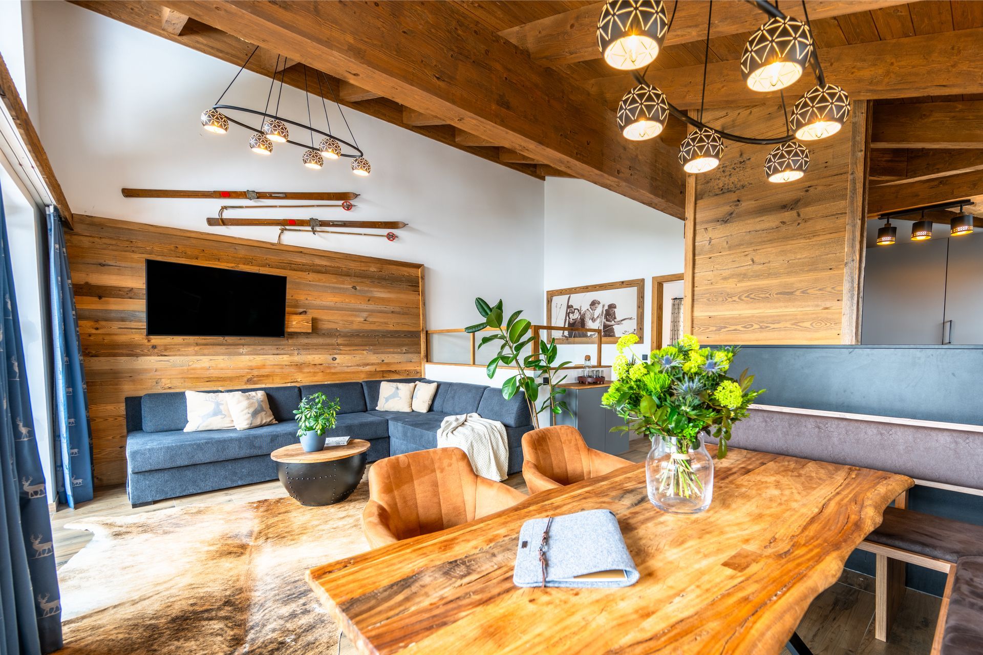 Loungebereich mit Holztisch, blauem Sofa und Akzentwand aus Holz.