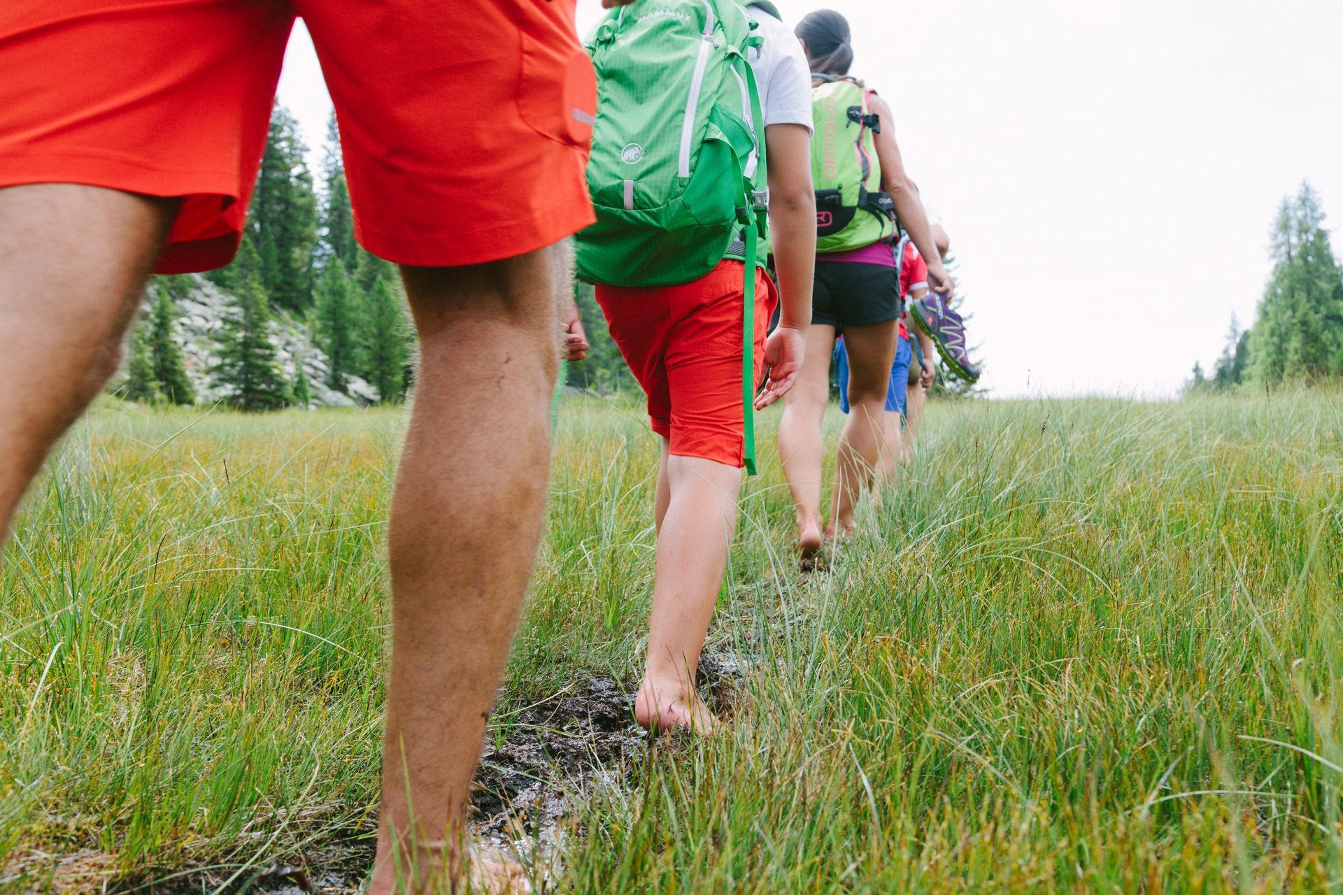Menschen wandern barfuß durch eine schlammige Wiese