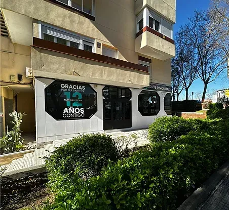 Exterior del edificio con escaparates, setos podados y un letrero que dice “Grâcia 73 Anos”.