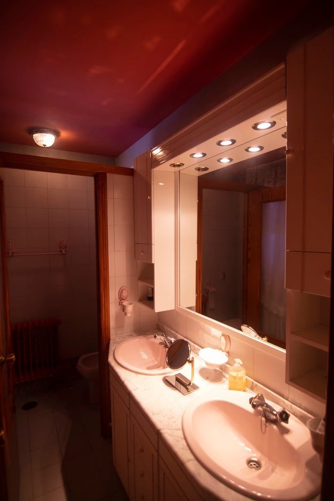 Mueble de baño en tonos cálidos con lavabo, espejo y luces de techo.