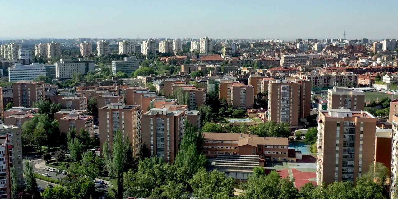 Amplio horizonte urbano con edificios de apartamentos, árboles y un cielo azul al fondo.