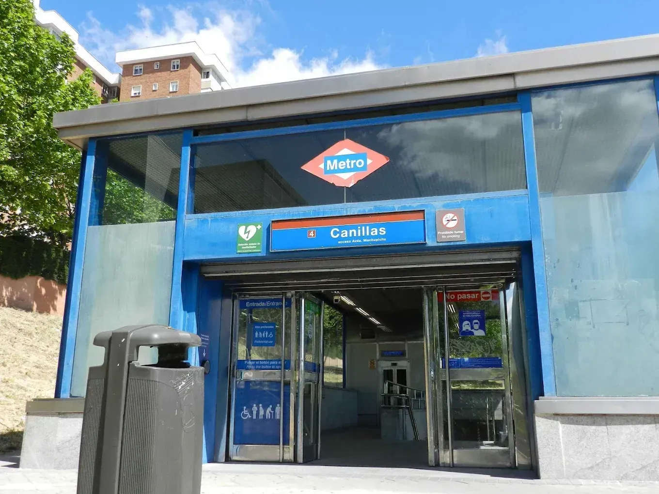 Entrada azul con fachada de cristal y un letrero de metro sobre la puerta.
