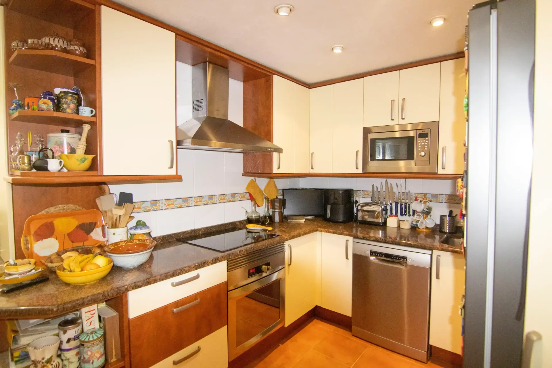 Cocina moderna con armarios de madera, electrodomésticos de acero inoxidable y suelo de madera.