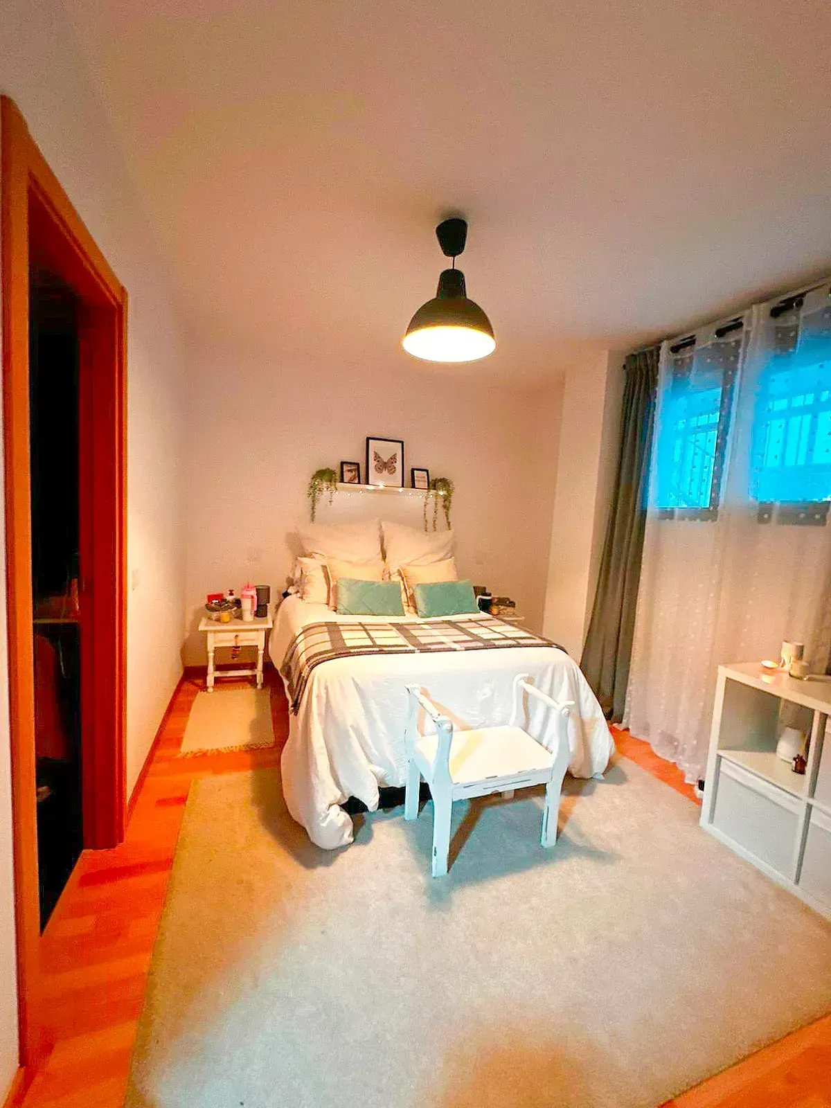 Habitación acogedora con cama, muebles blancos, paredes naranjas y ventana con cortinas.