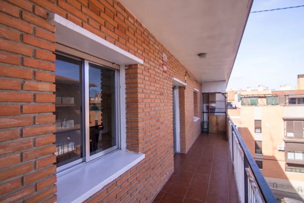 Apartamento de ladrillo con balcón, puertas corredizas de cristal y vistas a la ciudad.