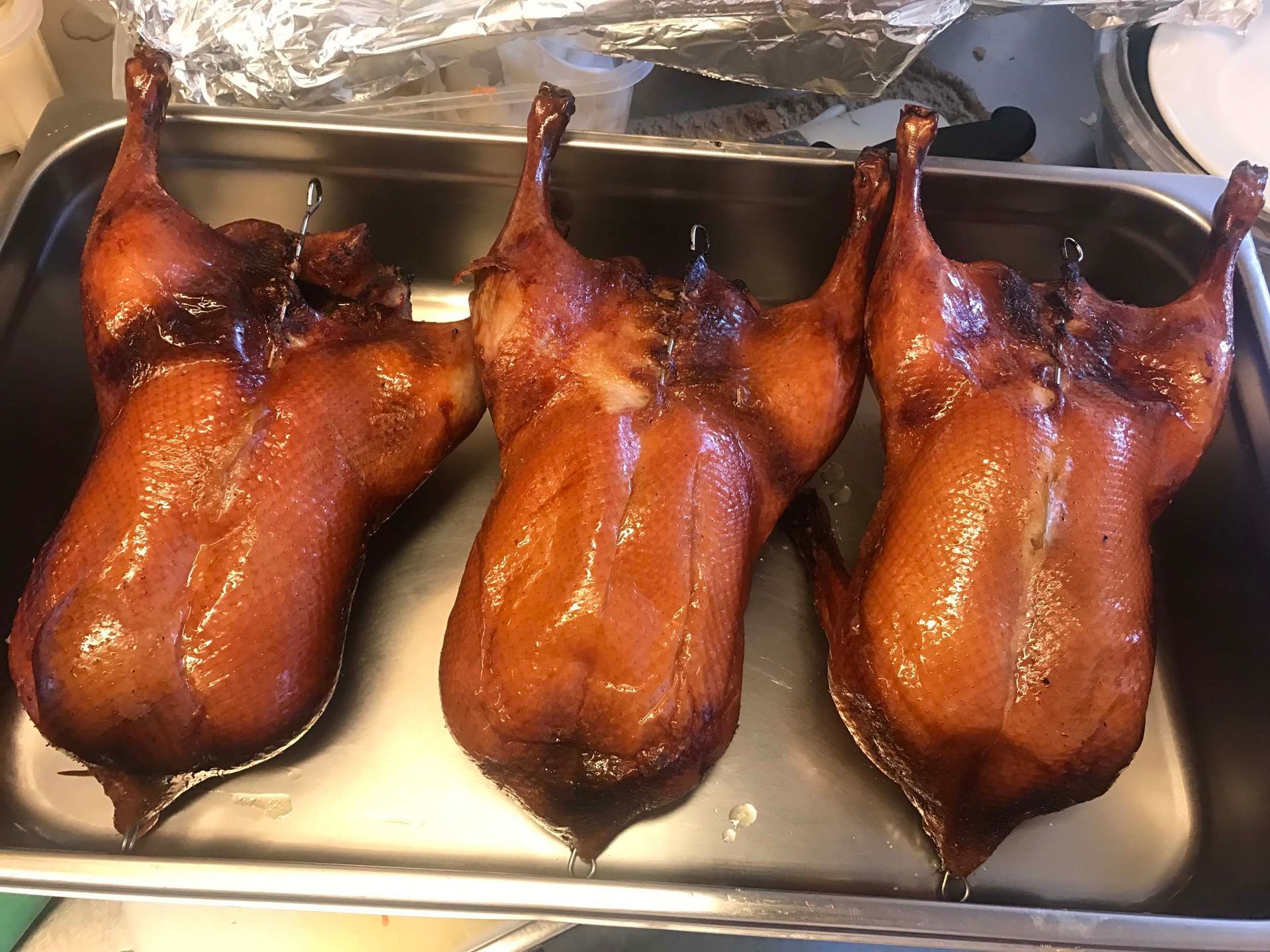 Drei gebratene Enten liegen in einer Metallpfanne.