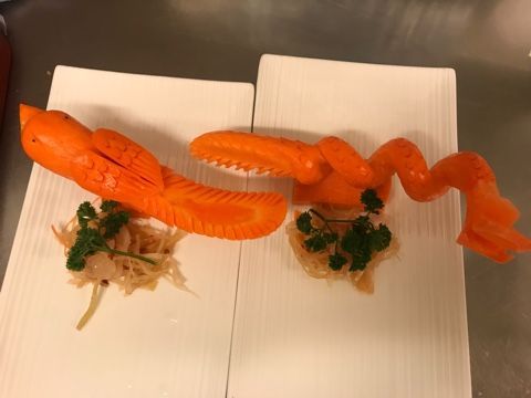 Zwei Teller mit Essen mit Karotten, die so geschnitzt sind, dass sie wie Hummer aussehen