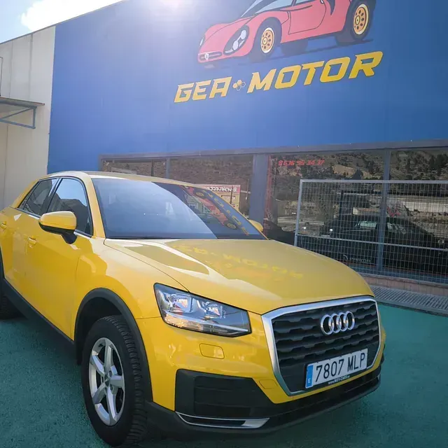 Un coche amarillo está aparcado delante de un cartel que dice ger motor