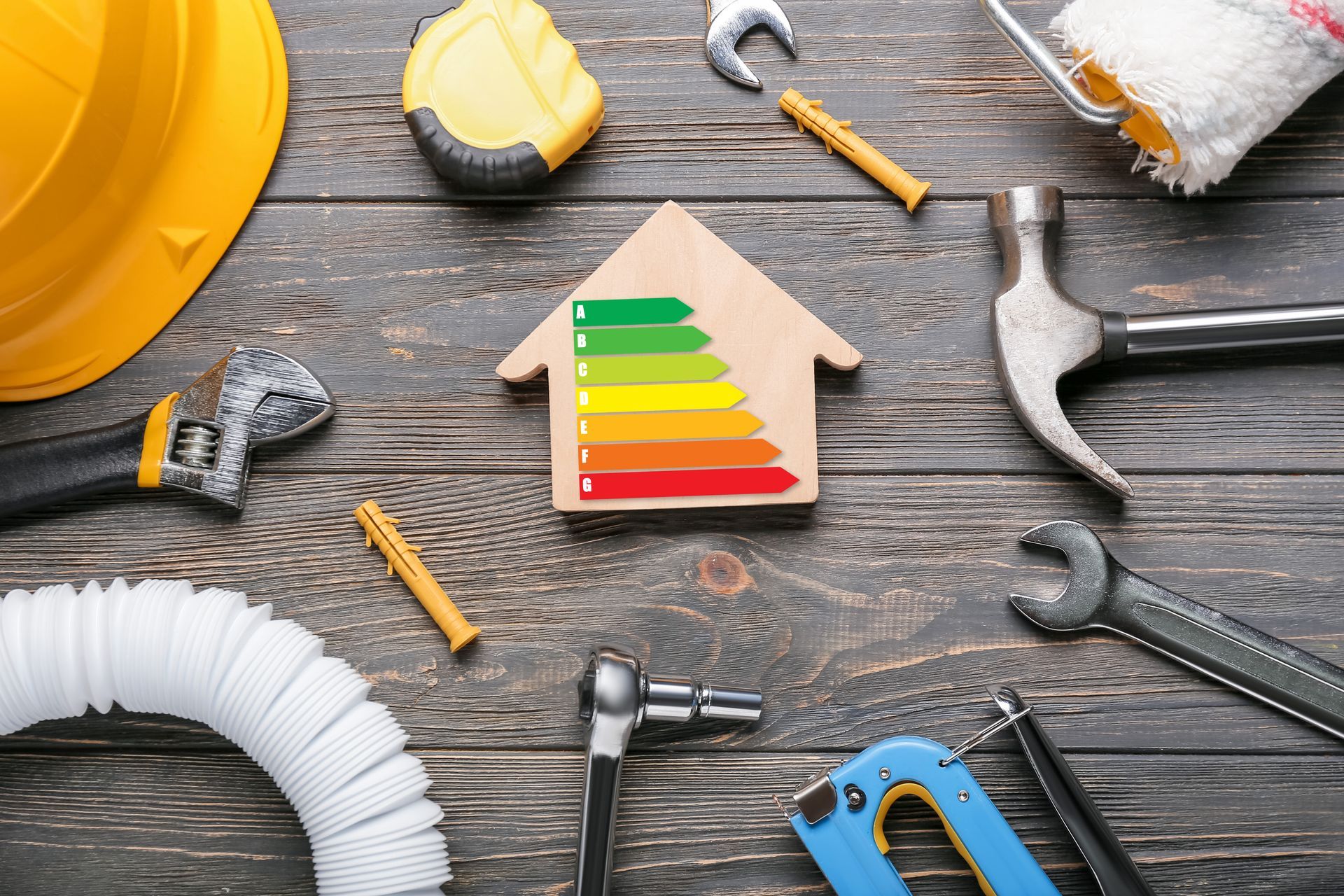 Vue sur une table avec de l'équipement de rénovation d'habitat et en son centre une maquette de maison en bois