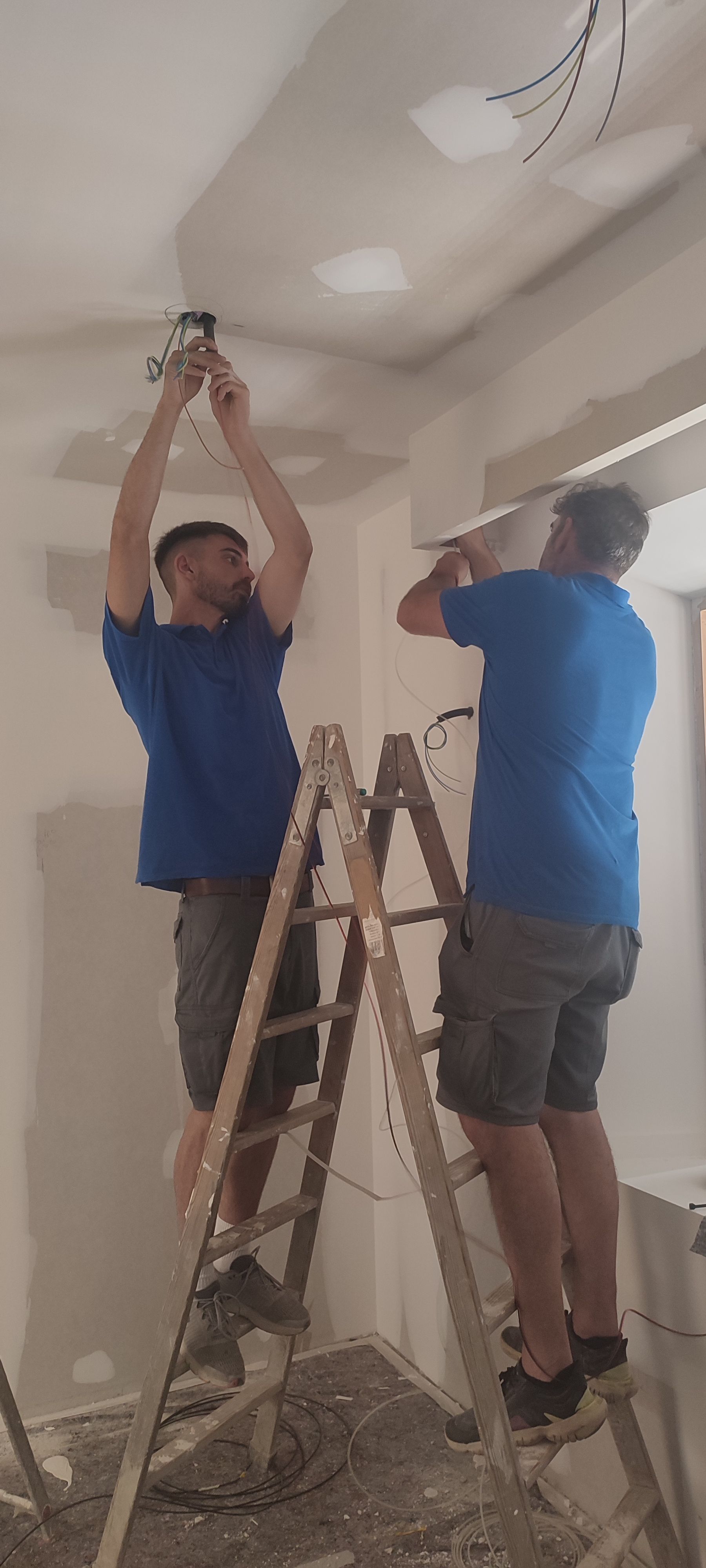 Dos hombres están de pie en una escalera trabajando en un techo.