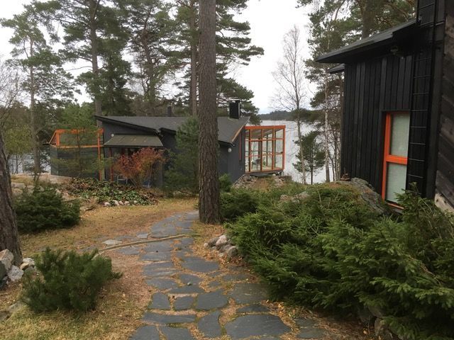 Kivinen polku johtaa pimeisiin mökkeihin järven rannalla, puiden ja pensaiden ympäröimänä.