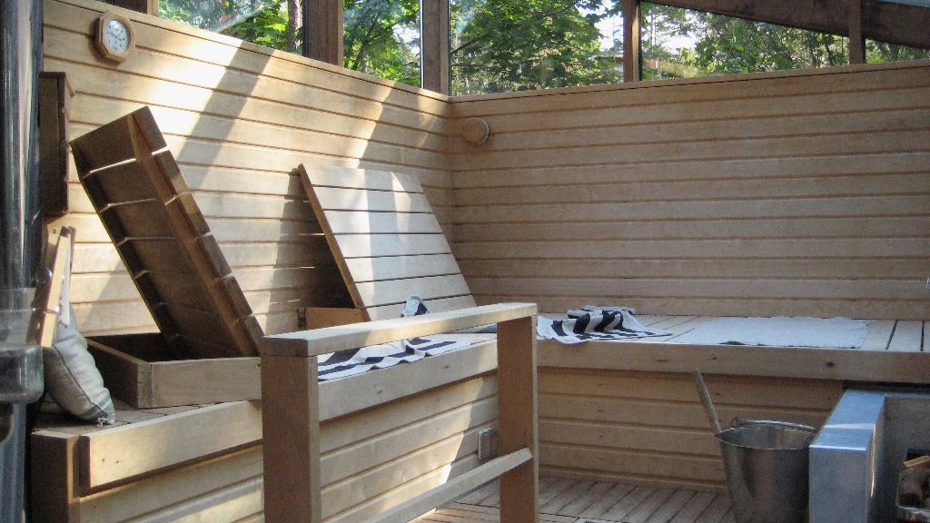 Puinen saunan sisustus, jossa on sälepohjaiset lauteet, pyyhe ja ämpäri.