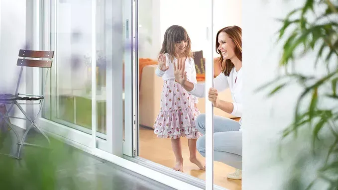 Eine Frau und ein kleines Mädchen stehen vor einer Glasschiebetür.