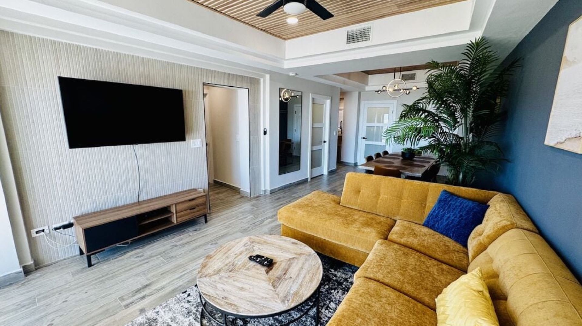 Living room with gray sectional sofa, coffee table, and rug. Open to kitchen and dining area with ocean view.