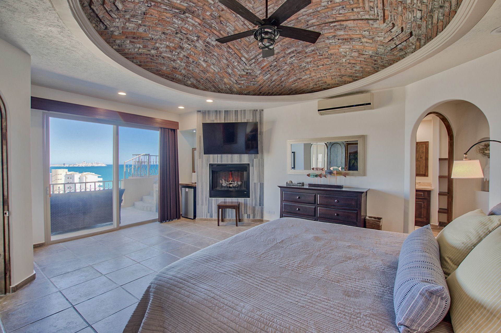 Bedroom with ocean view, fireplace, domed stone ceiling, and a large bed.