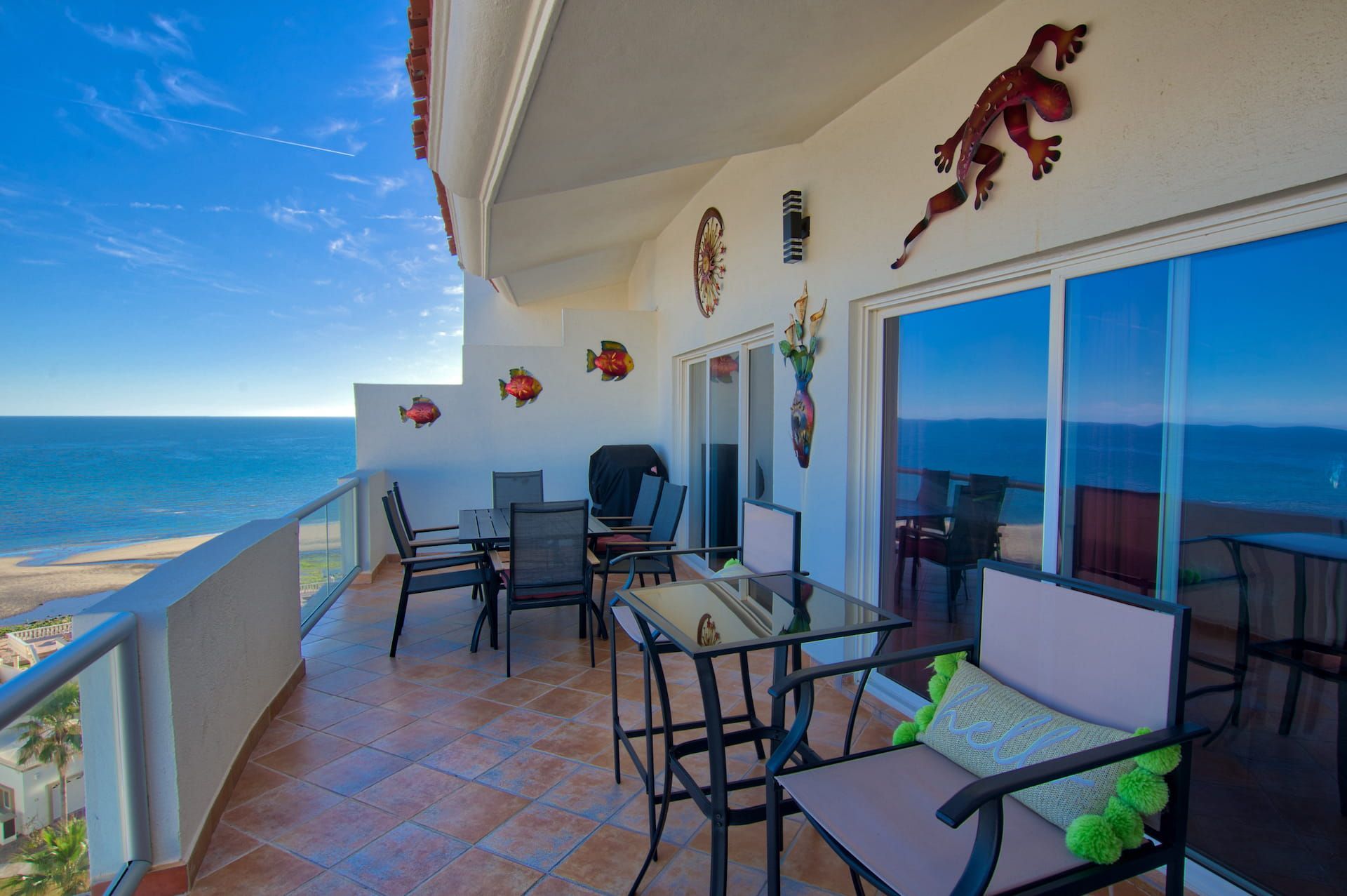 Balcony with ocean view, table, chairs, decorative art, and sliding glass doors.