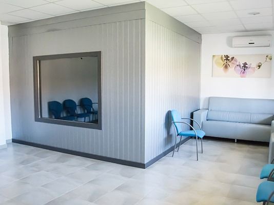 Una sala de espera con sillas azules y un sofá.