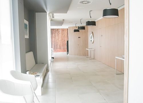 Un pasillo largo con un banco y sillas.