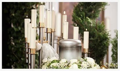 Una urna está rodeada de velas y flores en un funeral.