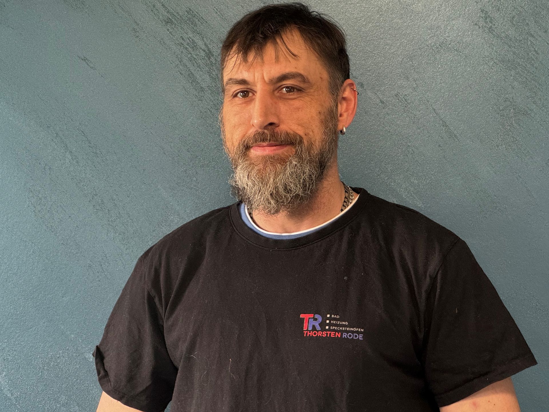 Ein mann mit bart trägt ein schwarzes t-shirt mit der aufschrift tn.