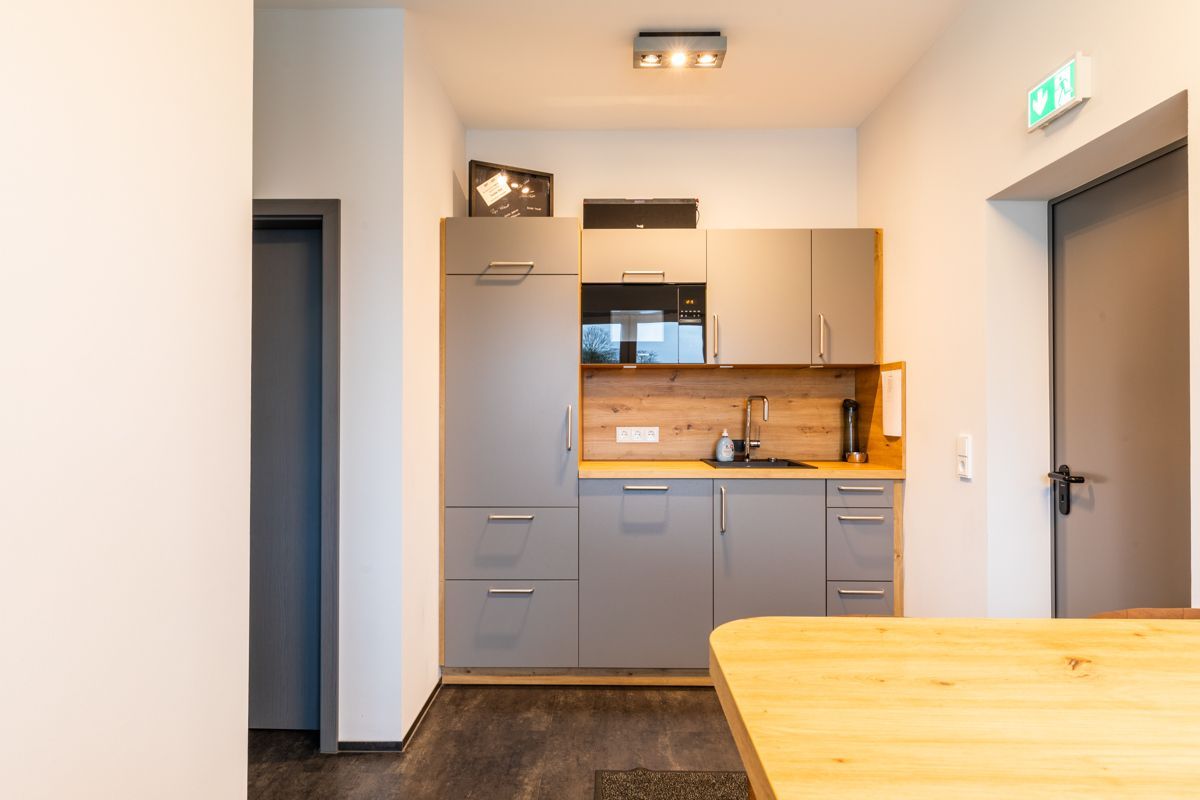 Eine Küche mit grauen Schränken und einem Holztisch.
