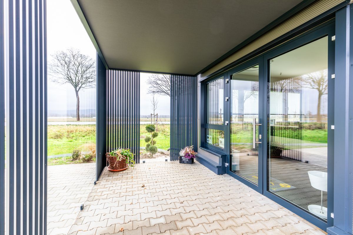 Es gibt eine Terrasse mit vielen Fenstern und einem Zaun.